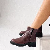 Bota corta de cuero vacuno color marrón, con suela track de goma negra, elástico lateral externo y cierre interno.