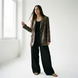 Blazer con estampado animal print de leopardo en tonos marrón y negro, con lentejuelas. Tiene solapa clásica y dos bolsillos frontales.