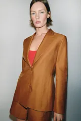 Blazer entallado color tostado confeccionado con lino. Cuenta con cuello solapa, manga larga con hombreras y cierre frontal con dos botones forrados a tono. Presenta forrería interior blanca.