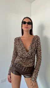 Top de fiesta color blanco, con escote drapeado y lentejuelas.