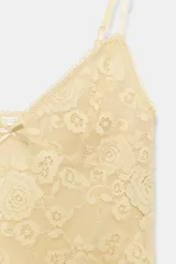 Top de encaje con escote en pico y tirantes finos ajustables. Presenta un pequeño lazo decorativo en el centro del escote y un diseño de encaje floral en toda la prenda.