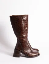 Botas de caña media de cuero vacuno color negro, con cierre lateral interno, taco de madera forrado en cuero y suela de goma.