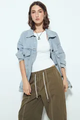 Pantalón tipo babucha de tiro bajo, color verde oliva, con silueta amplia y costuras visibles en contraste blanco. Posee cintura elástica con lazo blanco para ajuste.