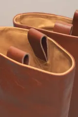 Bota de caña alta color marrón, confeccionada en cuero vacuno con forro y plantilla de cuero. Tiene suela de goma negra y un diseño de caña ancha.