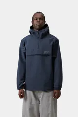 Campera impermeable estilo anorak Carhartt WIP modelo Windbreaker Pullover, color azul marino, con capucha ajustable, cierre frontal de media cremallera y bolsillo canguro frontal con solapa.