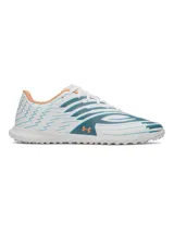 Championes de fútbol Under Armour Shadow Club 4 Turf, diseñados para césped artificial. Presentan un diseño en color blanco con detalles gráficos en azul y toques en naranja. Cuentan con empeine sintético, cordones centrales y suela de goma con tacos multidireccionales para un agarre óptimo.