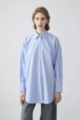 Camisa celeste a rayas verticales blancas, de corte oversize, manga larga y puños anchos.