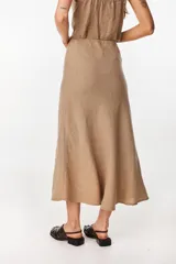 Falda larga color beige de corte sirena confeccionada en lino italiano, con pretina interior elástica y diseño fluido.