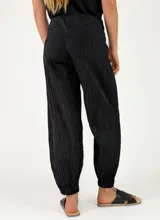 Pantalón beige con textura arrugada, de corte holgado estilo balloon con puños elásticos en los tobillos y cintura alta con faja y lazo ajustable.