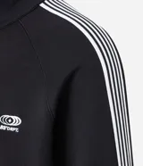 Campera deportiva de cuello alto con cierre frontal, confeccionada en tejido técnico con rayas laterales contrastantes y bordado localizado en el pecho.