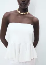Top peplum blanco sin mangas, con escote palabra de honor y diseño ajustado en el torso con vuelo en el bajo.