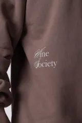 Buzo de cuello redondo y corte oversize, confeccionado en frisa suave. Presenta un diseño minimalista en color negro con un pequeño logo ovalado en el centro del pecho y una estampa sutil en el lateral inferior derecho.