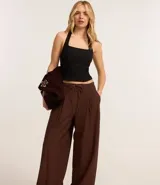 Pantalón wide leg de estilo sastre color marrón, con cintura elástica, lazo ajustable y pliegues frontales. Presenta un corte recto y fluido.