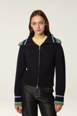 Cárdigan de punto azul marino con cierre frontal de cremallera. Presenta cuello tipo camionero y puños con detalles de rayas en tonos verde y celeste. El tejido tiene una textura acanalada con detalles calados decorativos.