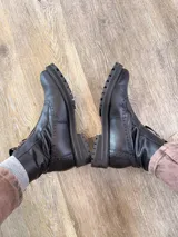 Botas de cuero color marrón con diseño estilo brogue, cierre lateral y suela track negra de goma resistente.