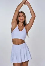 Conjunto deportivo compuesto por un top de escote en V con breteles finos y una pollera corta tableada con cintura alta.