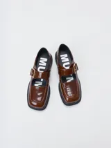 Zapatos tipo guillermina Mutma modelo Punko, color marrón, confeccionados en cuero. Presentan punta cuadrada, detalle texturizado en la parte delantera, tira en el empeine con hebilla metálica dorada y suela chunky de goma negra con taco bajo.