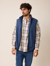 Camisa de manga larga con cuello abotonado y cierre frontal de botones. Presenta un diseño de cuadros en tonos beige, blanco y azul con líneas finas en rojo.