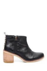 Botin de cuero negro con textura combinada de cuero liso y cuero croco. Presenta un diseño de caña baja con cierre lateral y detalle de animal print en la parte posterior. Cuenta con un taco cuadrado de madera y suela con costura vista.
