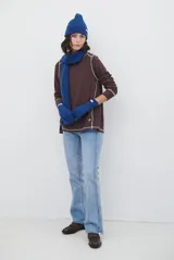 Remera de manga larga en color beige, confeccionada en tejido de punto con costuras a la vista en contraste. Presenta un corte holgado, cuello redondo y un pequeño bordado distintivo en la parte inferior.