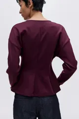 Top de tejido suave con efecto neopreno, escote en V y diseño de cintura entallada. Presenta hombros caídos, mangas largas y puños ajustados.