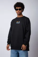 Buzo negro de corte oversize con cuello redondo, confeccionado en tela rústica. Presenta un pequeño estampado central en el pecho que muestra un avión arrastrando un cartel y olas debajo.