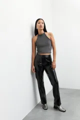 Pantalón negro de cuero sintético, tiro alto, corte oxford y costuras verticales a lo largo de las piernas.