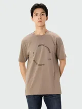 Camiseta de manga corta color beige con cuello redondo y un estampado gráfico en el pecho con texto que incluye "ARCTIC X-TREME" y coordenadas geográficas.