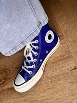 Zapatillas de lona color beige, tipo bota, con cordones marrones, puntera de goma y logo de peach engomado.