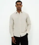 Camisa comfort de manga larga y cuello inglés, confeccionada en mezcla de lino y algodón. Presenta un diseño básico sin estampa con cierre frontal de botones.