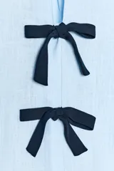 Camisa celeste de lino con escote en pico y manga corta abullonada. Cierre frontal con dos lazos negros a contraste.