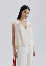 Blusa naranja sin mangas con escote en V y detalle de frunces en los hombros.