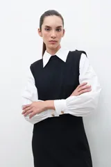 Vestido midi negro de tejido de punto, sin mangas, con cuello redondo y hombreras.