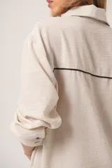 Camisa color beige con bordado de ramas en el frente, de corte holgado y manga larga.