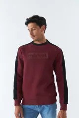Buzo color bordó con cuello redondo y mangas largas con detalle de franja negra en los hombros. Tiene puños y logo "Mistral" estampado en relieve en el pecho.