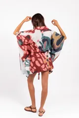 Vestido camisero oversize de tela calada con estampado abstracto multicolor, cuello camisero, mangas anchas y lazo ajustable en la cintura confeccionado en la misma tela.