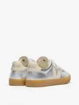 Zapatillas Veja modelo Recife, color plateado metalizado con cierre de tres tiras de velcro. Presentan el logo de la marca en color crema en el lateral y suela de goma color caramelo.