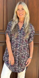 Camisa de fibrana con estampado paisley multicolor sobre fondo azul, de corte holgado, manga corta y cierre frontal con botones.