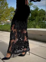 Falda larga de terciopelo negro con diseño ajustado en la parte superior y ruedo con transparencias de encaje floral y red.
