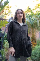 Camisa tejida en punto calado con hilo de algodón y lurex, de silueta oversize. Presenta mangas 3/4 ligeramente abullonadas, cuello camisero clásico y cierre frontal con botones metálicos.