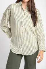 Camisa de corte oversize con estampado de rayas verticales, cuello clásico, cierre frontal con botones y bolsillo en el pecho. Presenta mangas largas con puños abotonados y un diseño fluido.