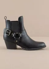 Bota corta de estilo texano en color negro, con taco cuadrado y punta redondeada. Presenta una tira decorativa con hebilla metálica y una argolla lateral que rodea el tobillo, aportando un toque distintivo al diseño.