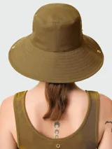 Sombrero tipo bucket color verde oliva, confeccionado en algodón, con detalles de ojales metálicos dorados y logo de la marca en el lateral.