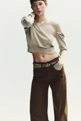 Jersey de punto con cuello en V y manga larga. Presenta un diseño versátil con detalles de acabados desmontables mediante botones en la parte inferior y en los hombros.
