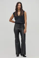 Pantalón de cuero negro, de corte ajustado en la parte superior y acampanado en la parte inferior.