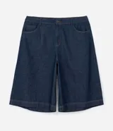 Bermuda tipo jorts de corte amplio y tiro medio, confeccionada en denim de algodón azul oscuro. Presenta diseño de cinco bolsillos, cierre frontal con botón y costuras en tono contrastante.