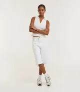 Blusa sin mangas de color blanco, con cuello polo y escote en V, confeccionada en algodón con elastano.