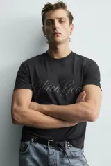 Remera negra de corte cropped, con cuello redondo y manga corta. Presenta estampado frontal con texto en efecto desgastado.