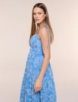 Vestido midi color azul con bordado broderie floral en tono blanco, escote recto con tirantes finos de lazo para anudar, corte ajustado en la cintura y falda escalonada holgada con bolsillos laterales.