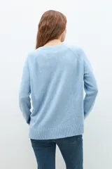 Sweater de punto en color celeste, con cuello redondo, mangas largas y puños acanalados. Presenta un diseño de corte holgado con costuras verticales decorativas en el frente.